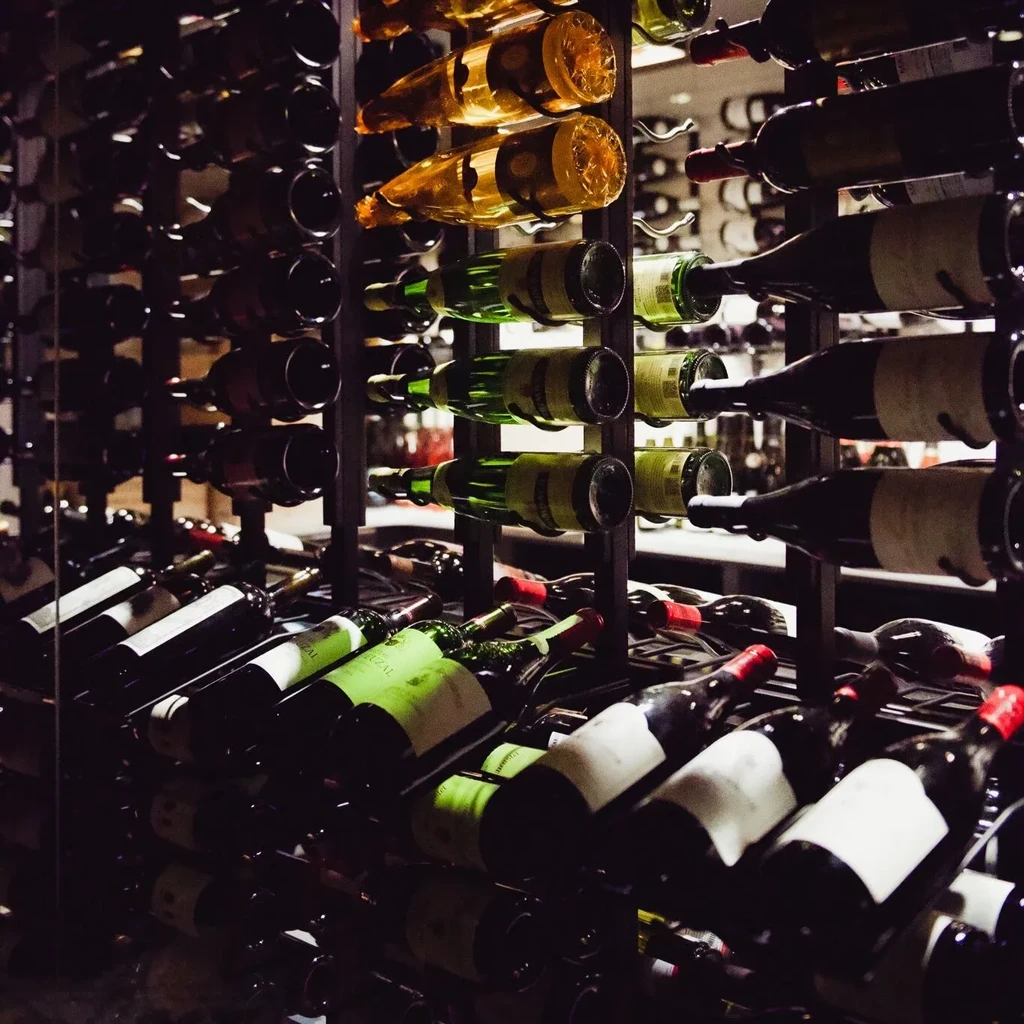 Vast, dim wine cellar with hundreds of diverse bottles on shelves.