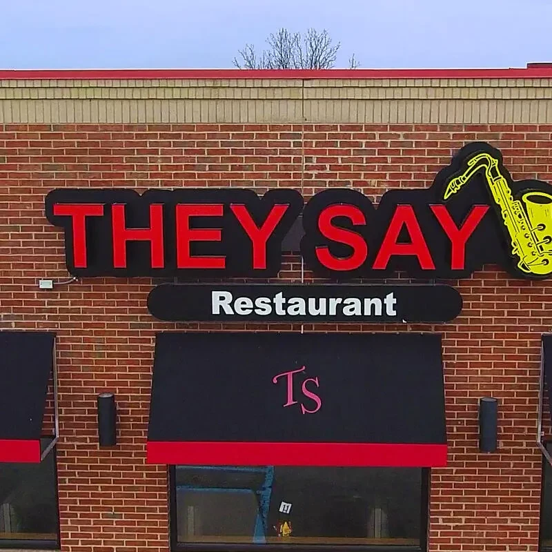 Reddish-brown brick They Say Restaurant facade with saxophone graphic.