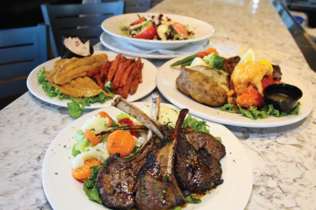 Four restaurant dishes: lamb, fried fish, lobster, and salad.