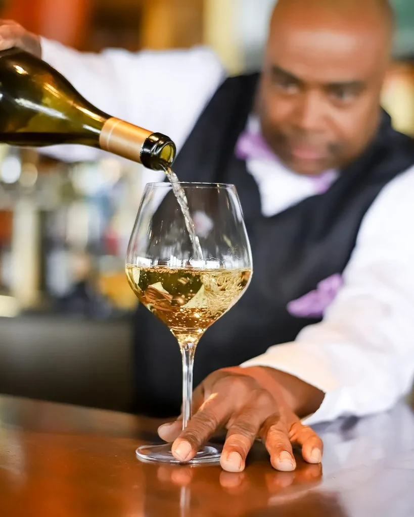White wine actively pours from a green bottle into a glass.