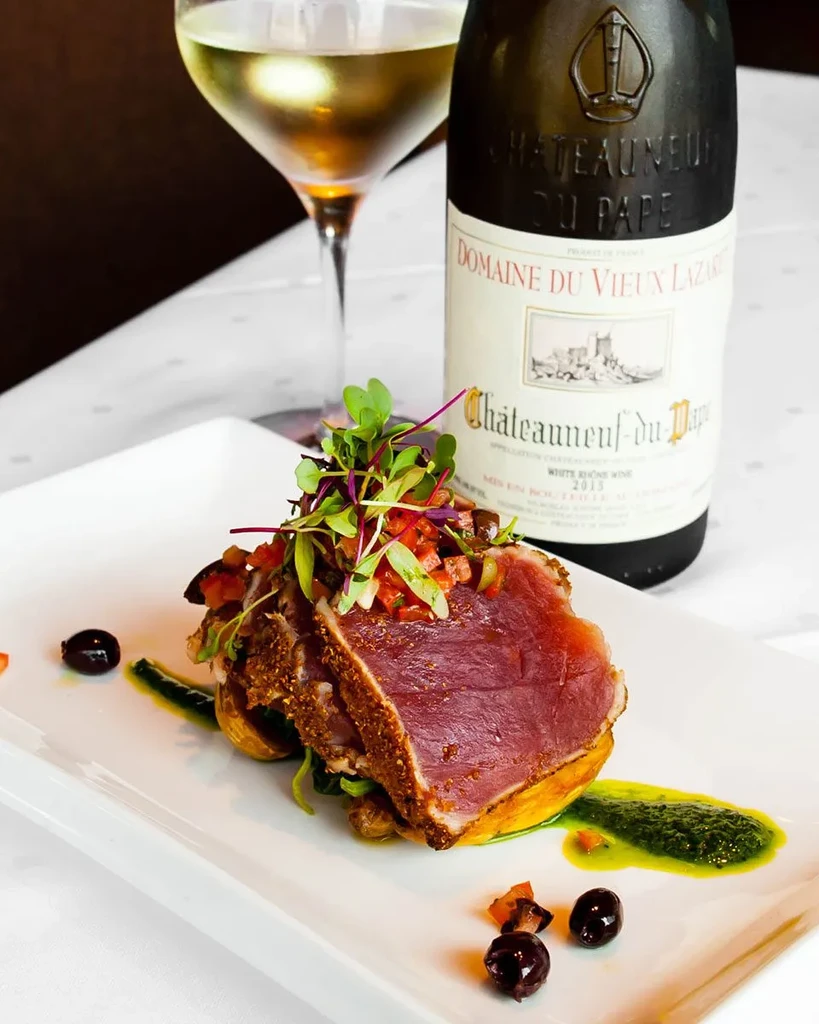 Plated seared tuna, relish, white wine glass, and Chateauneuf du Pape bottle.