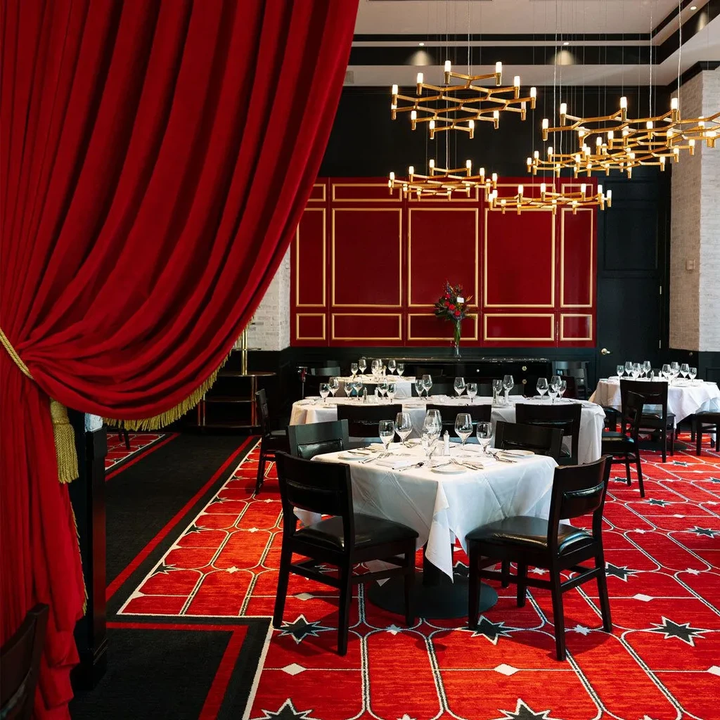 Lavish, empty dining room with red velvet, gold chandeliers, and star carpet.