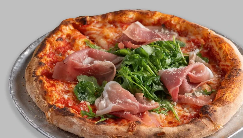 Neapolitan pizza with tomato, cheese, arugula, prosciutto, and grated cheese.