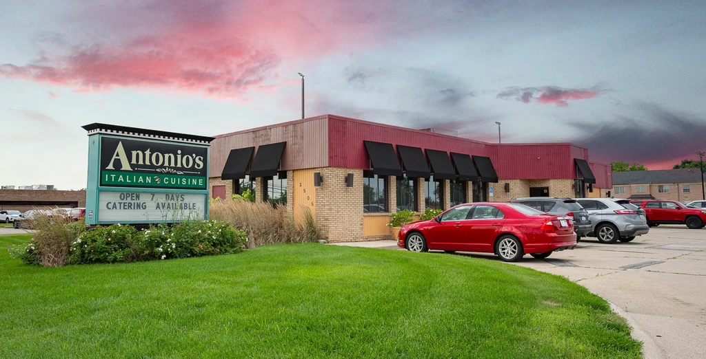 Antonio's Italian Cuisine restaurant building with sign under dramatic red sky.