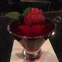 Dark red martini with sugared rim, berry garnish, and hidden bat symbol.