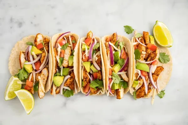 Five chicken tacos with chicken, avocado, onion, tomato, cilantro, and lime.