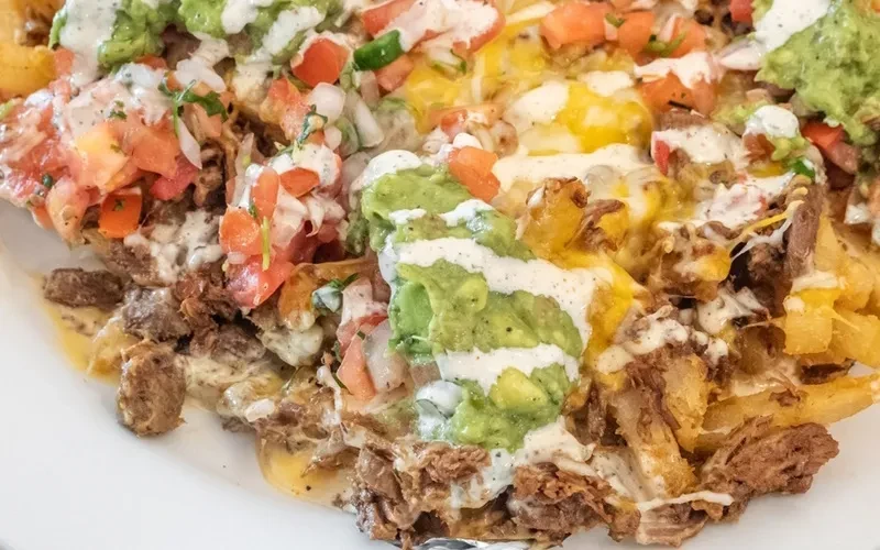 Overhead shot: Loaded carne asada fries with beef, cheese, guacamole, pico.