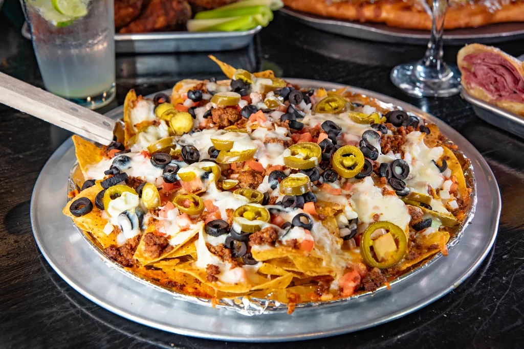 Nachos topped with cheese, ground meat, olives, tomatoes, and jalapeños.
