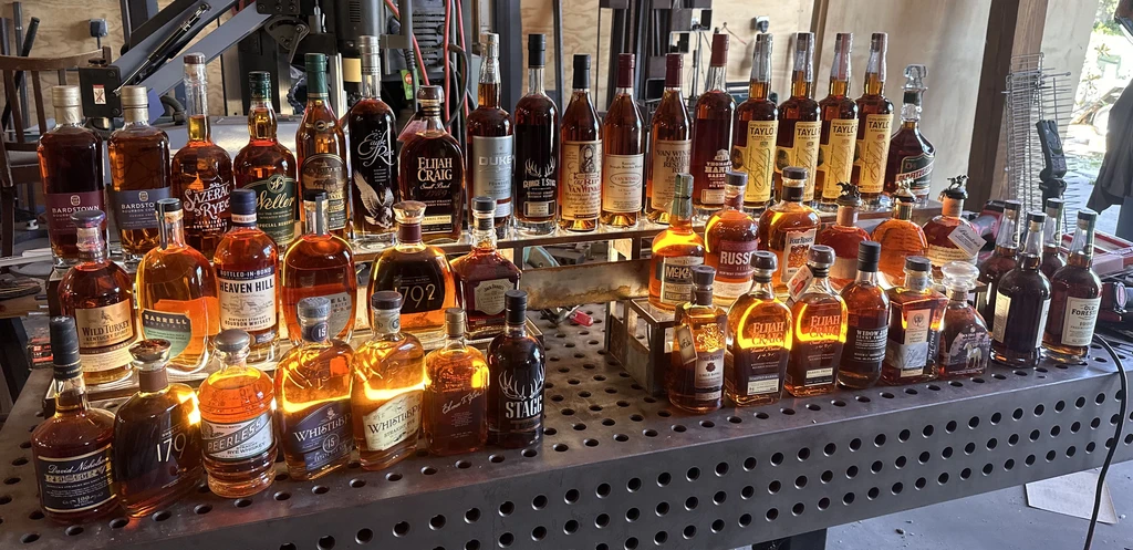 Dozens of whiskey bottles on a two-tiered industrial metal display.