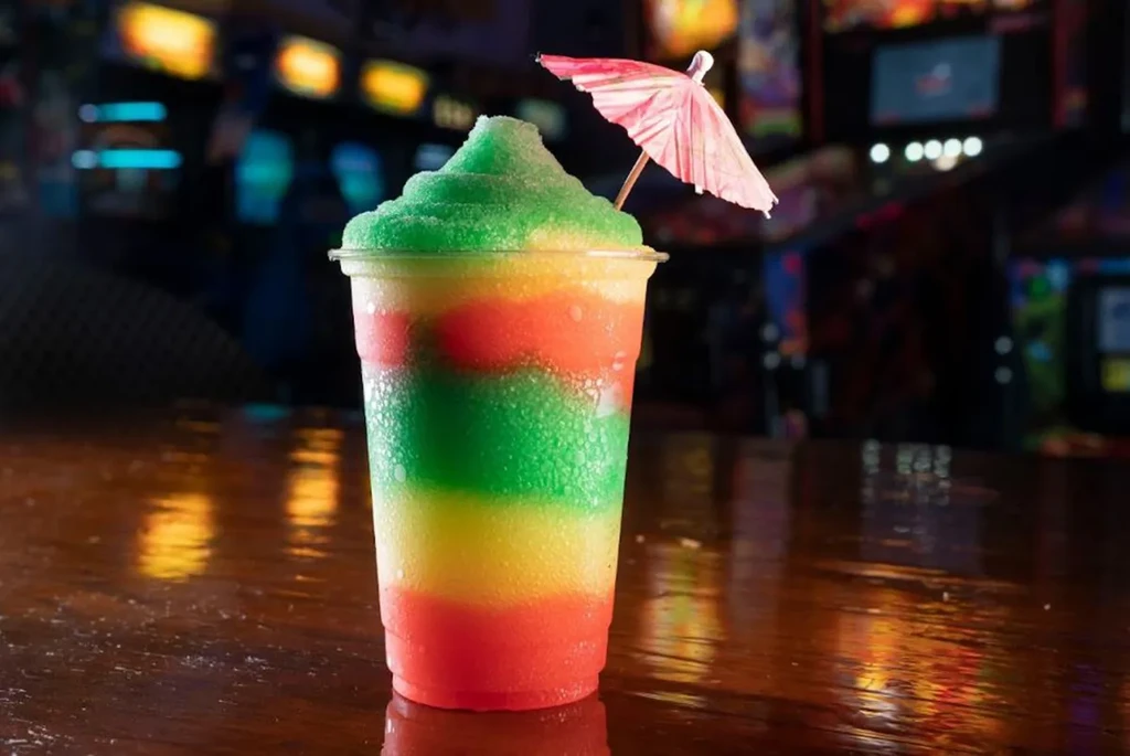 Three-layered red, yellow, green frozen drink with cocktail umbrella.
