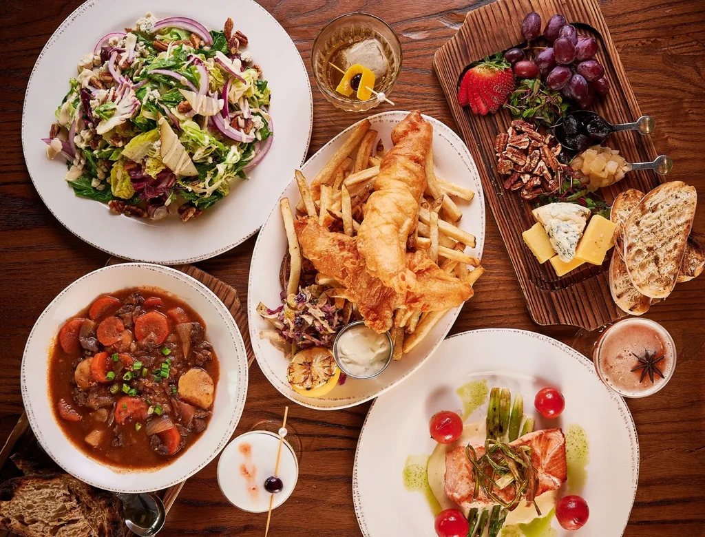 Overhead: rustic table laden with diverse, artfully presented food and drinks.