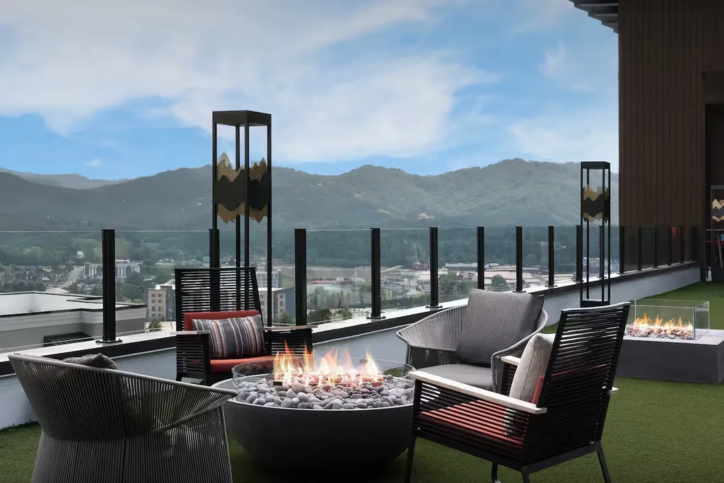 Outdoor rooftop lounge with two fire pits and panoramic mountain views.