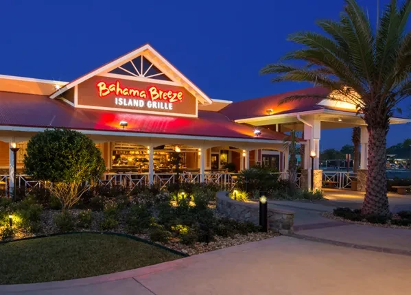 Bahama Breeze Island Grille exterior at twilight, brightly lit and tropical.