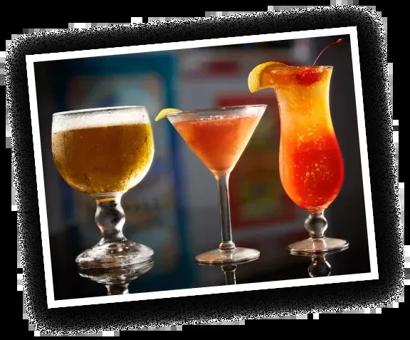 Golden beer, reddish martini, and layered orange cocktail on a bar.
