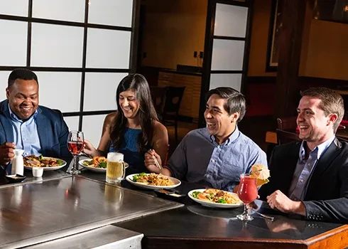 Four adults laughing and dining at a hibachi restaurant.