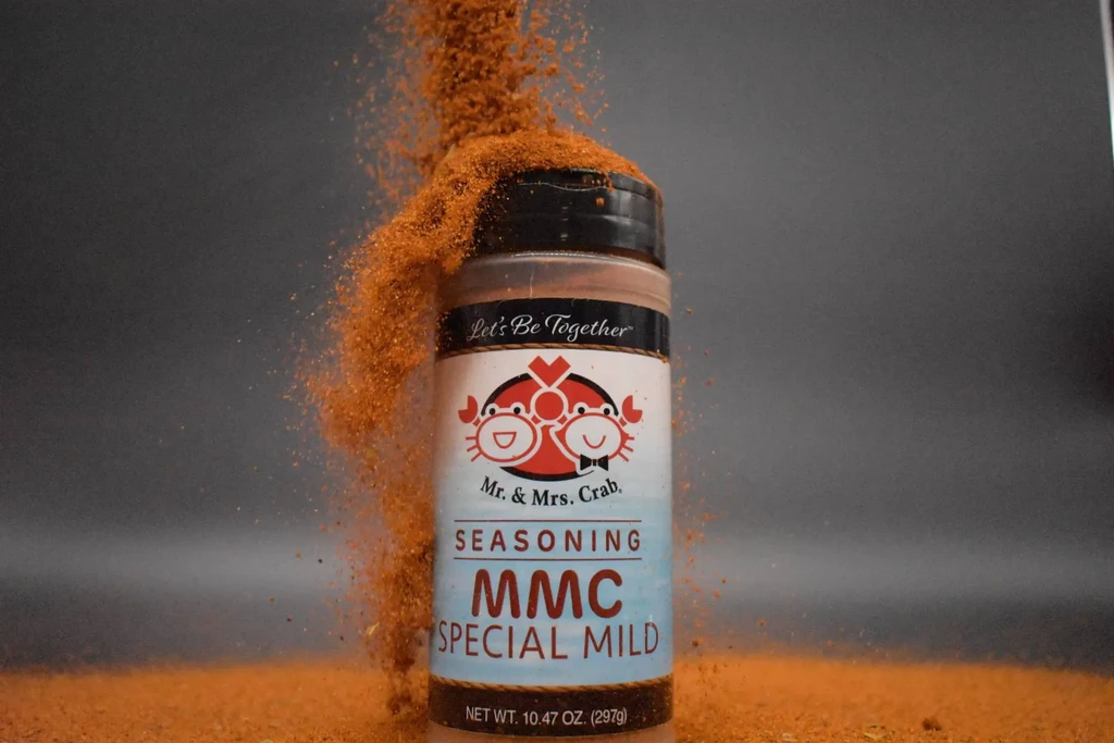Seasoning pouring over a "Mr. & Mrs. Crab" spice jar.