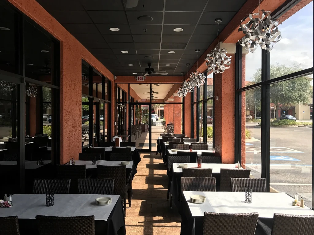 Empty covered patio restaurant interior with rustic walls and large windows.