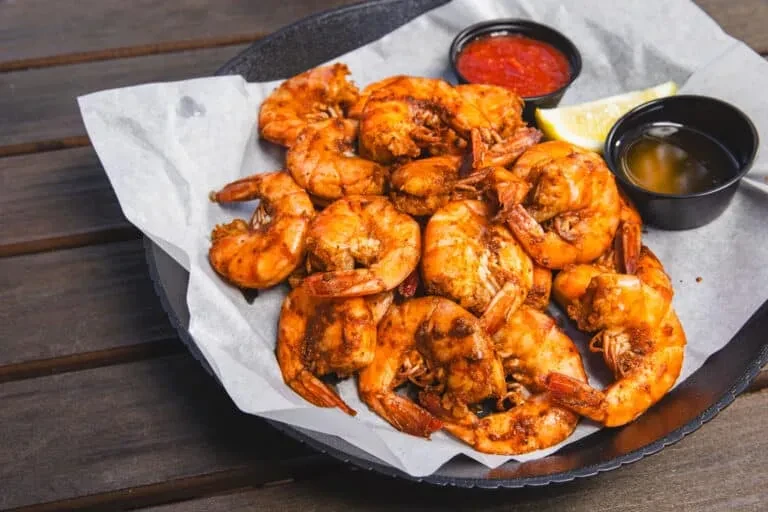 Cooked seasoned shrimp, red sauce, yellow liquid, and lemon.