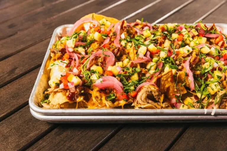 Loaded nachos with meat, melted cheese, pineapple, and pickled onions.