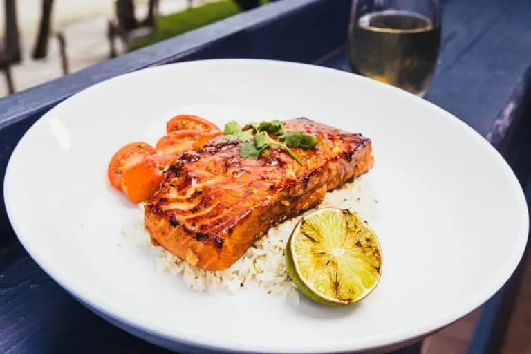Grilled salmon with rice, cherry tomatoes, charred lime, and herbs.