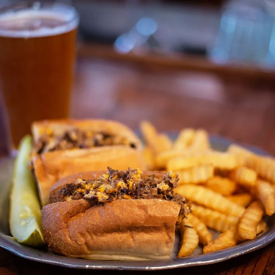 Open-faced meat and cheese sandwiches, crinkle fries, and a pickle spear.