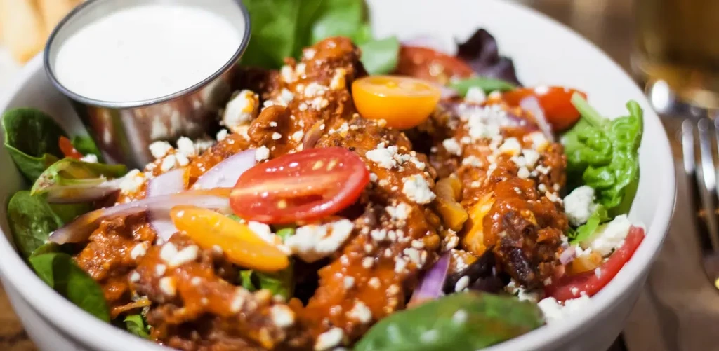 Buffalo chicken salad with crumbled blue cheese, greens, and dressing.