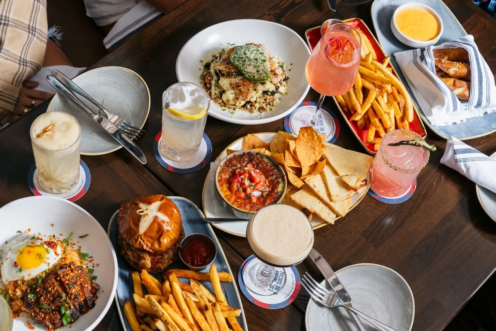 Overhead view of a wooden table with varied food and drinks.