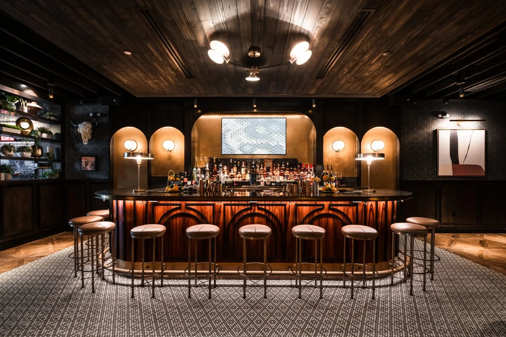 Dimly lit, sophisticated bar with dark wood counter and liquor display.