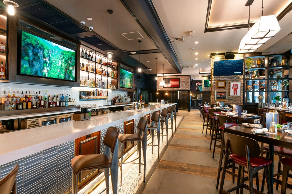 Warmly lit modern bar and restaurant interior with dining area.