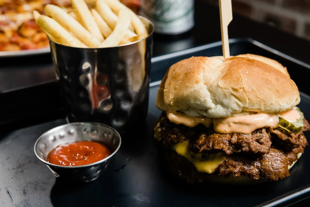 Two-patty burger with cheese, sauce, pickles, fries, and ketchup.