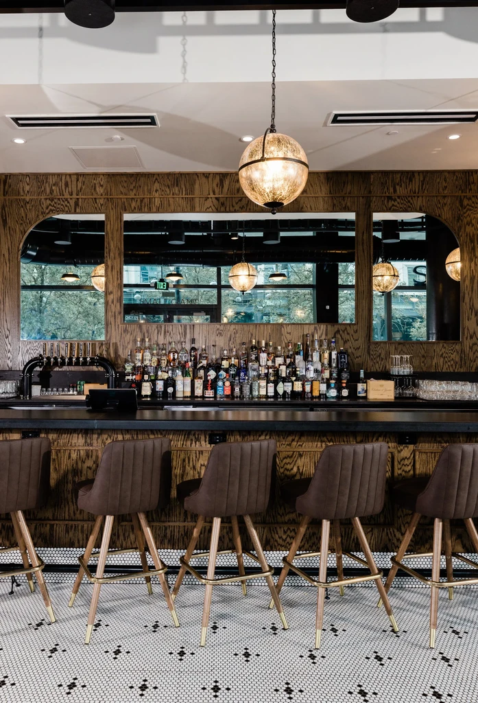Empty stylish bar interior featuring beer taps, liquor bottles, hexagonal floor.