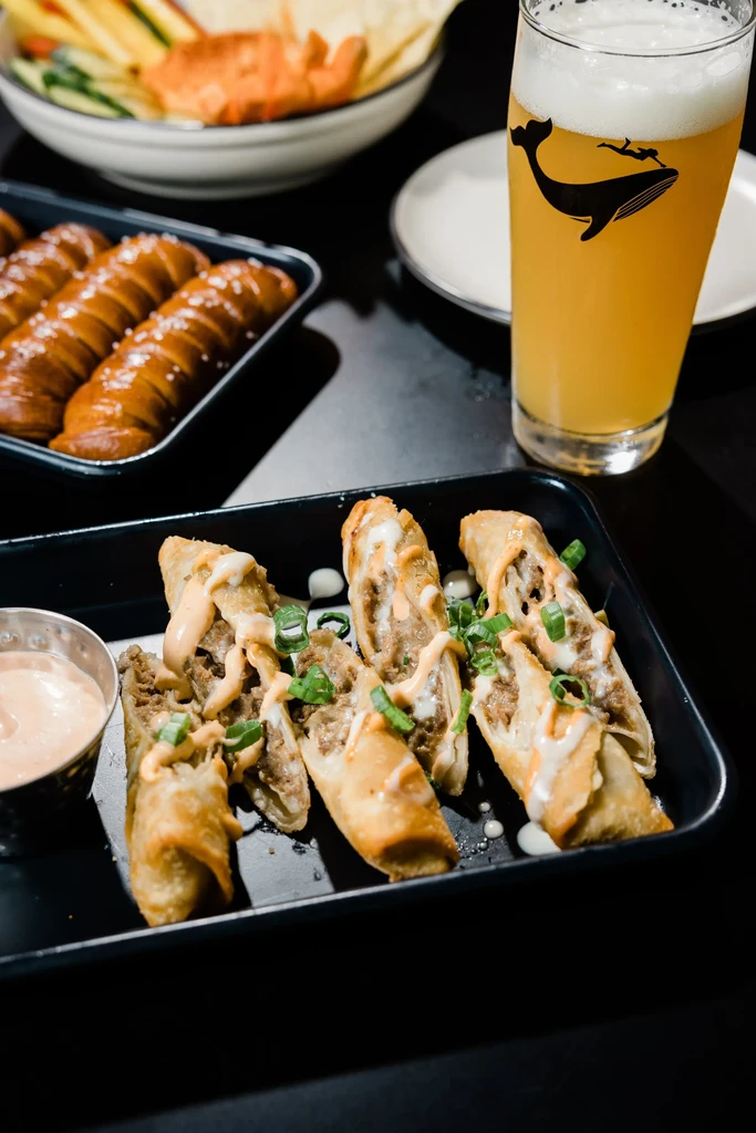 Close-up: fried rolls, pretzel sticks, and beer with a whale logo.