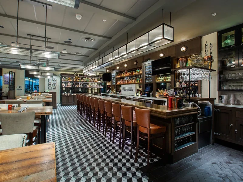 Well-stocked modern bar and dining room with warm lighting, no people.
