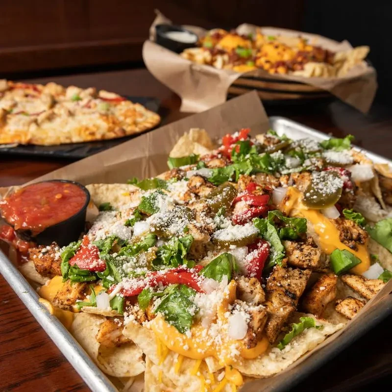Loaded chicken nachos piled high with cheese, vegetables, and salsa.