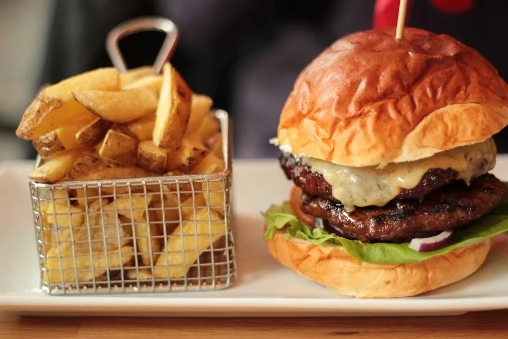 Double cheeseburger with melted cheese and crispy potato wedges.
