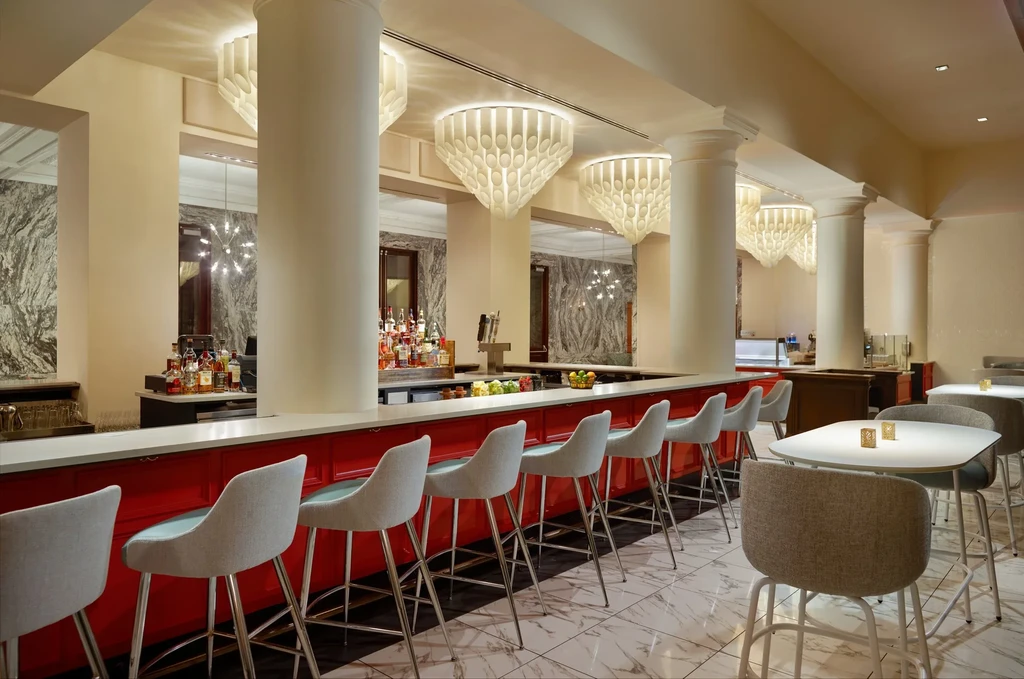 Modern empty bar with red counter, contemporary stools, marble walls.