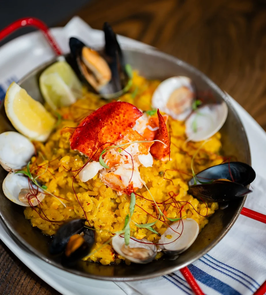 Vibrant seafood paella in a pan with lobster, mussels, and clams.