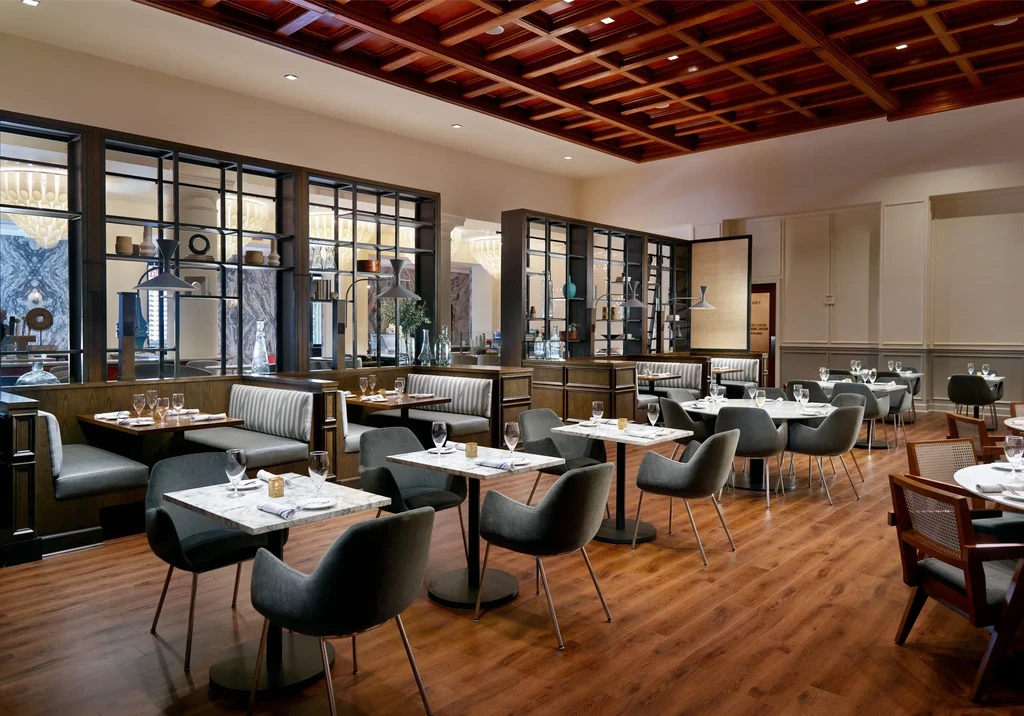 Modern, elegant restaurant dining room with green booths and dark wood ceiling.