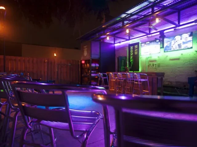 Purple and green neon-lit bar with stools and BAD MONKEY sign.