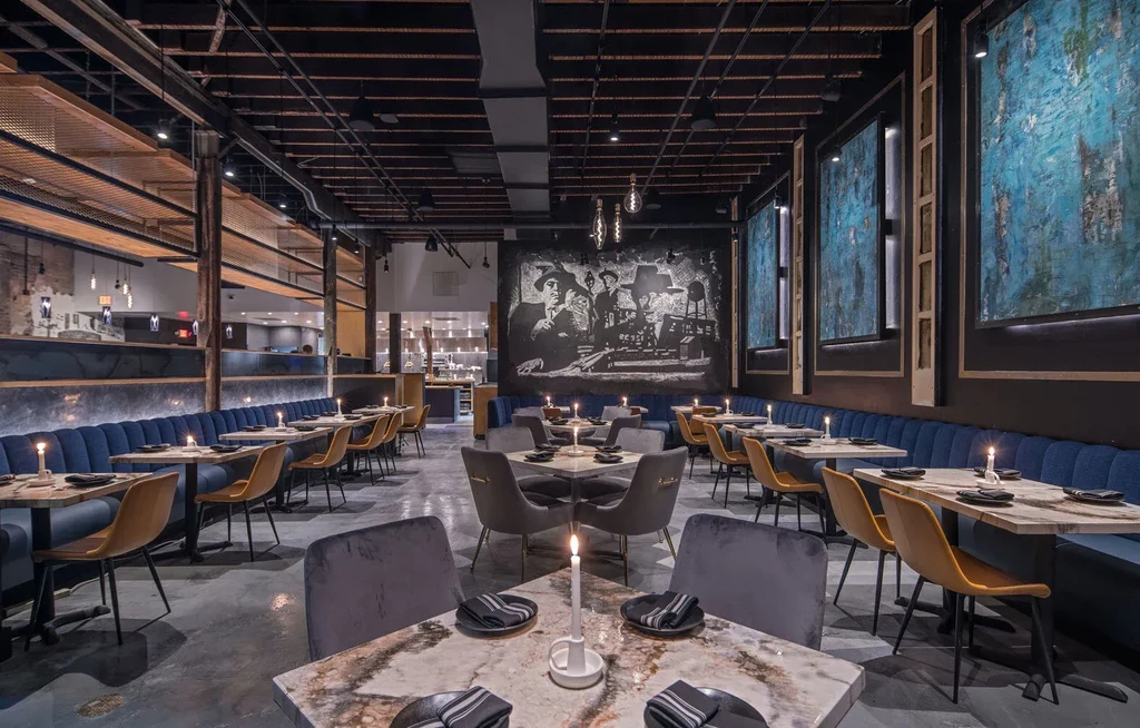 Elegant, industrial-chic restaurant interior with tufted booths and marble tables.