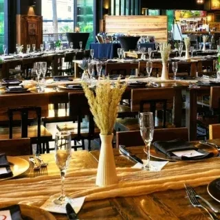 Empty rustic-chic dining room with long wooden tables elegantly set.