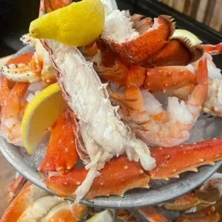 Cooked crab legs, shrimp, and lemon on an iced seafood platter.