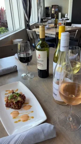 Plated appetizer, red, white, and rosé wines on a restaurant table.