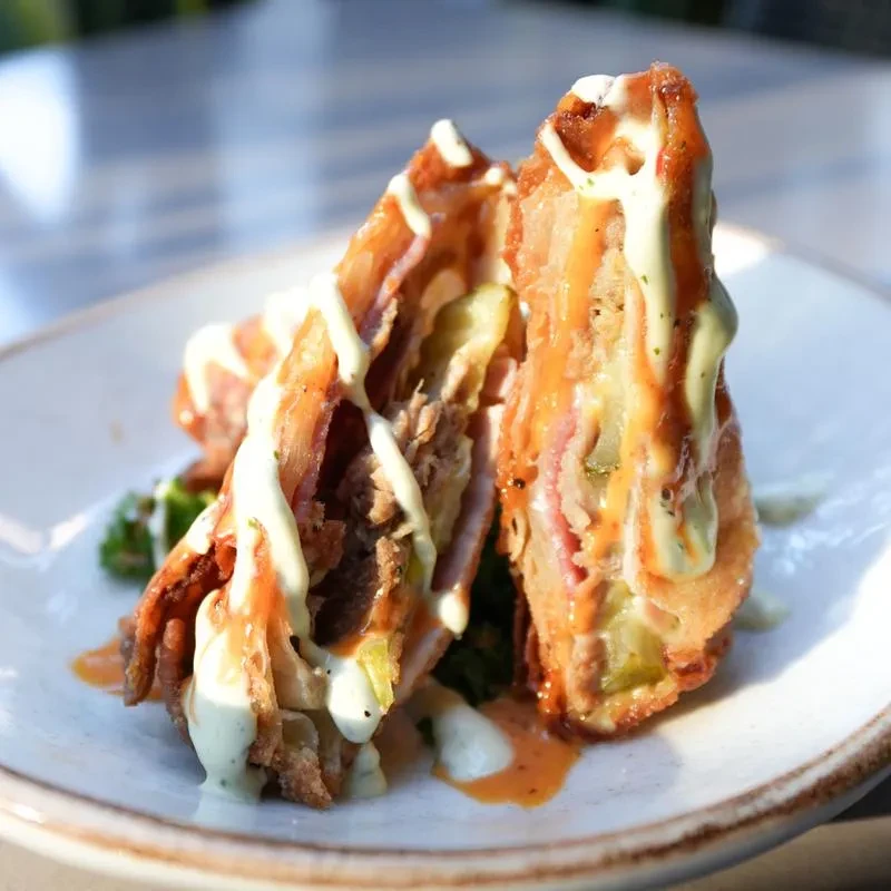 Two crispy fried pork and ham halves with pickles and sauces.