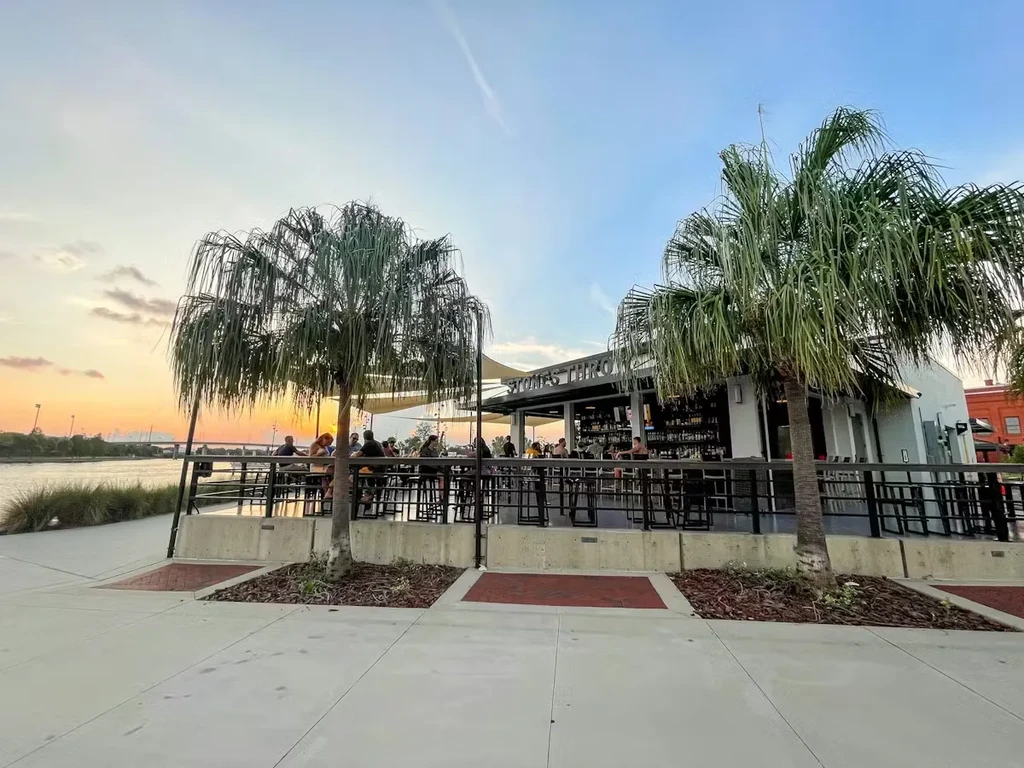 Sunset view of Pigman's waterfront restaurant patio with palm trees.