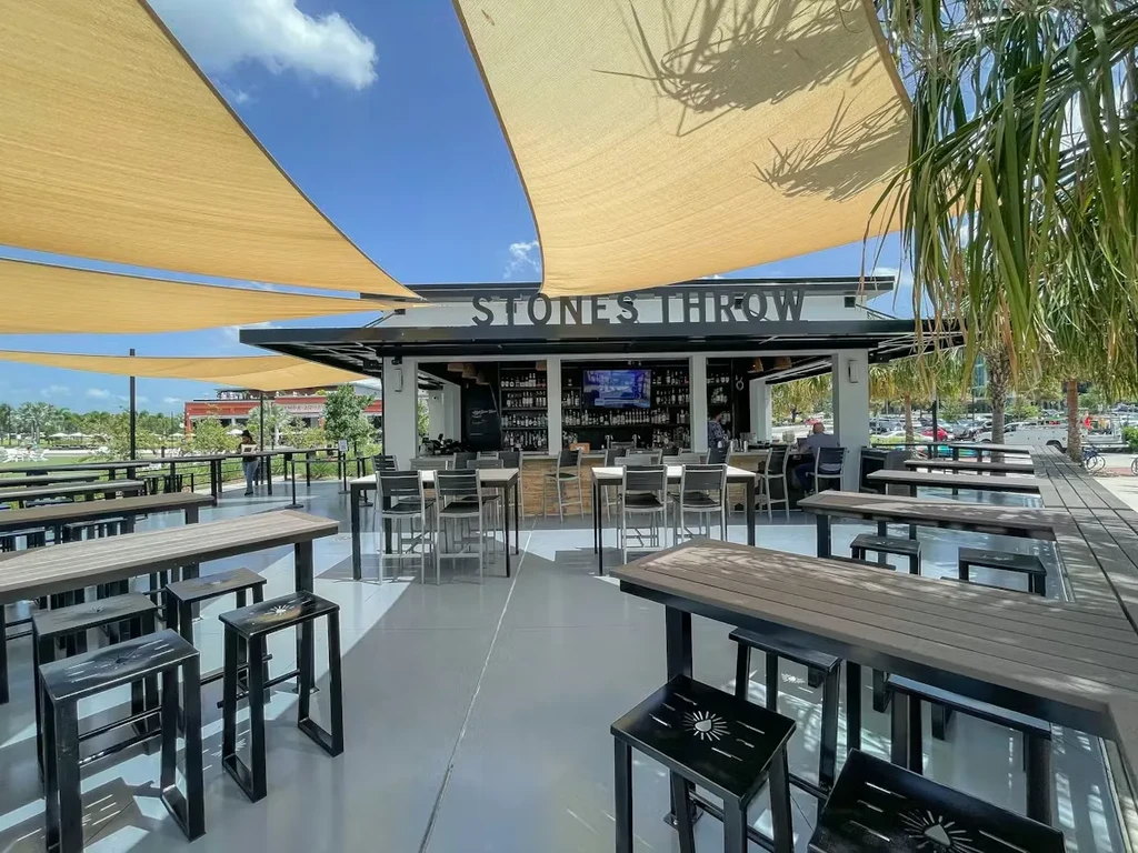 Stone's Throw outdoor bar, shade sails, seating, palm trees, waterfront.