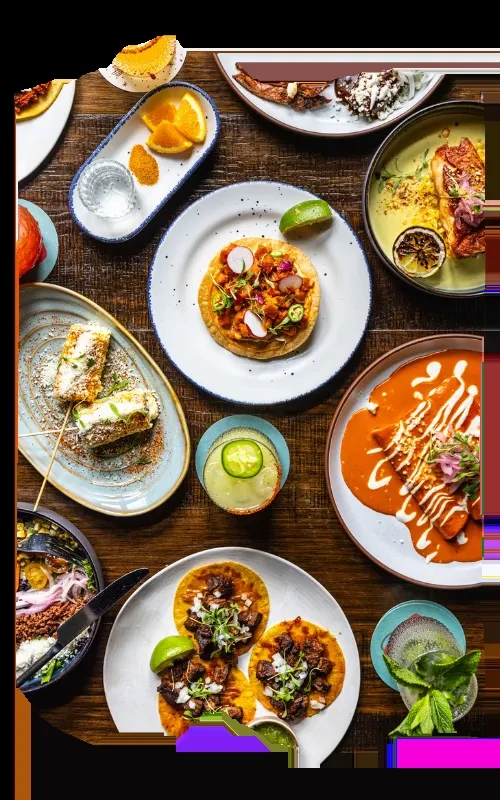 Overhead shot of rustic table laden with colorful Mexican food and drinks.
