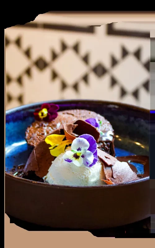 Chocolate dessert with ice cream, chocolate curls, colorful pansy flowers in a bowl.