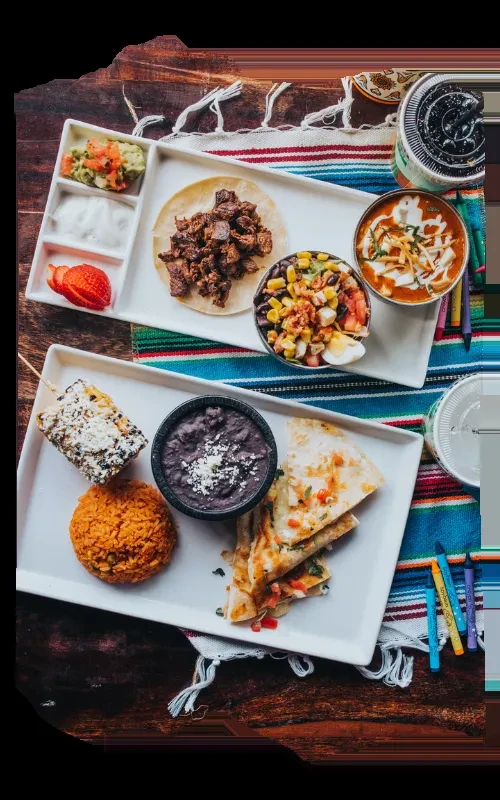 Overhead view of two plates with colorful Mexican food on a striped runner.