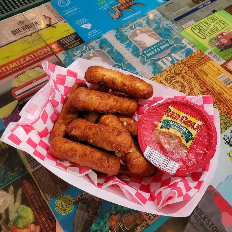 Basket of fried cheese with marinara and beer label background.